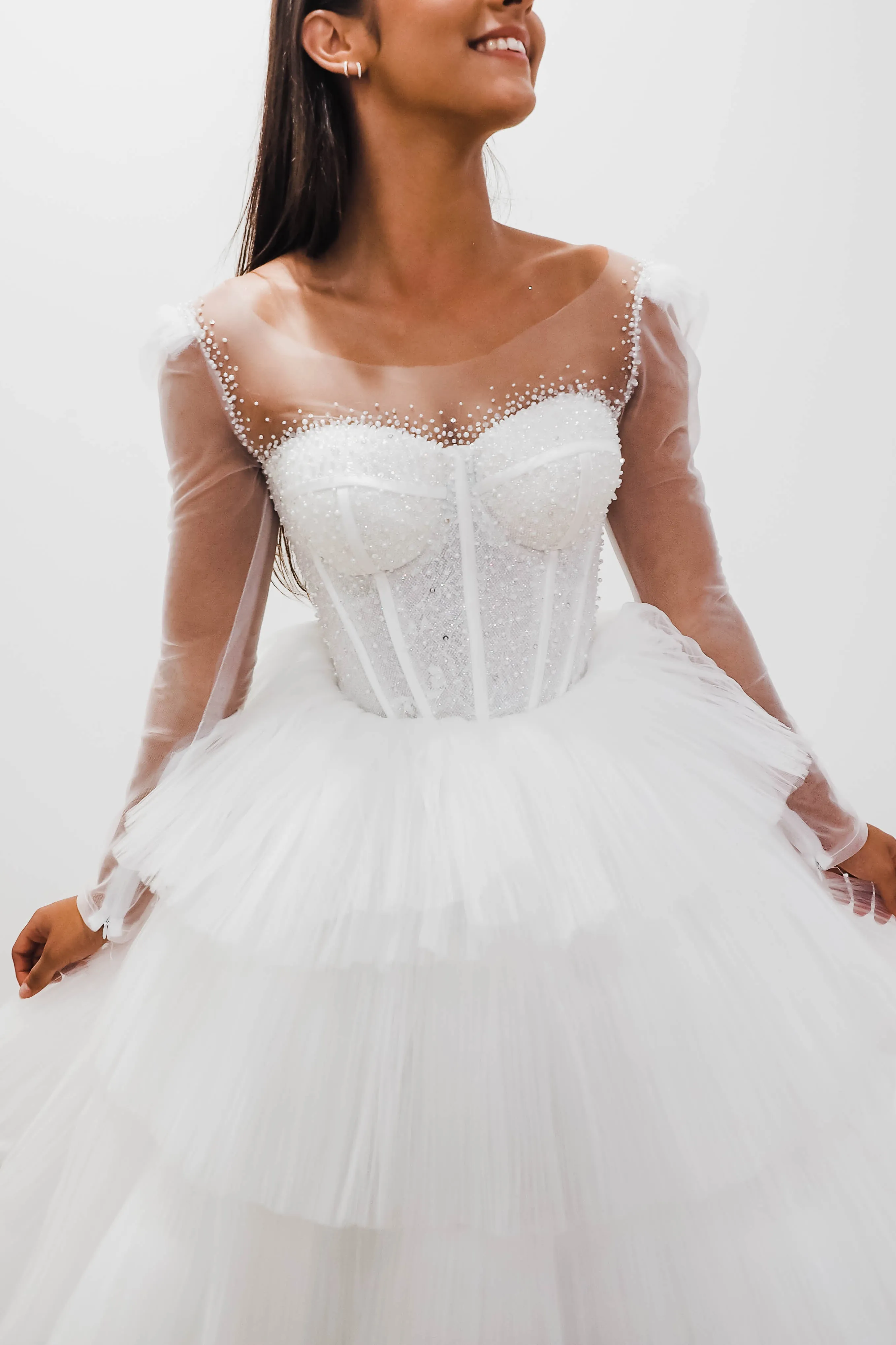 White wedding dress with a bushier top and a bushier puffy layered skirt.