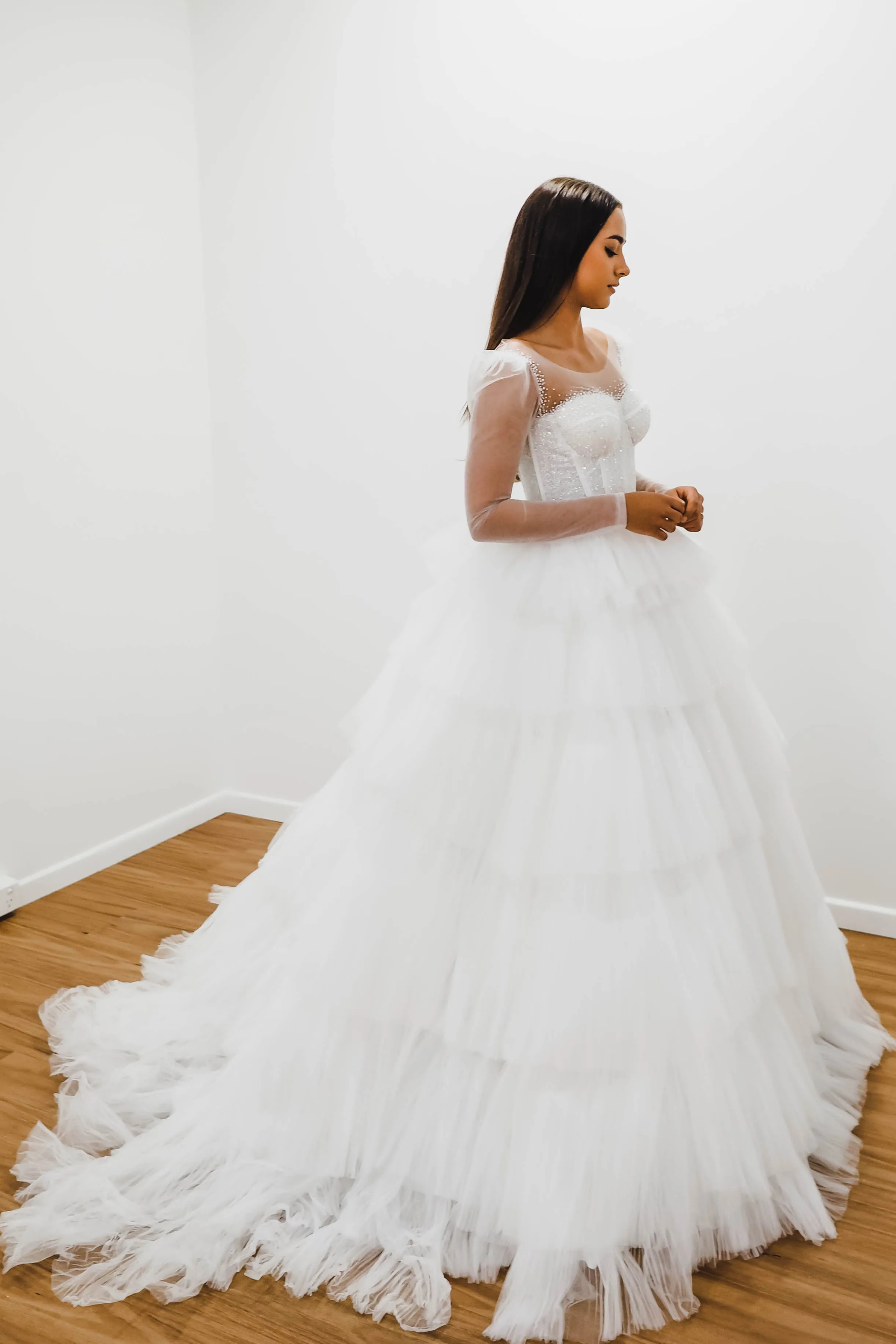 White wedding dress with a bushier top and a bushier puffy layered skirt.