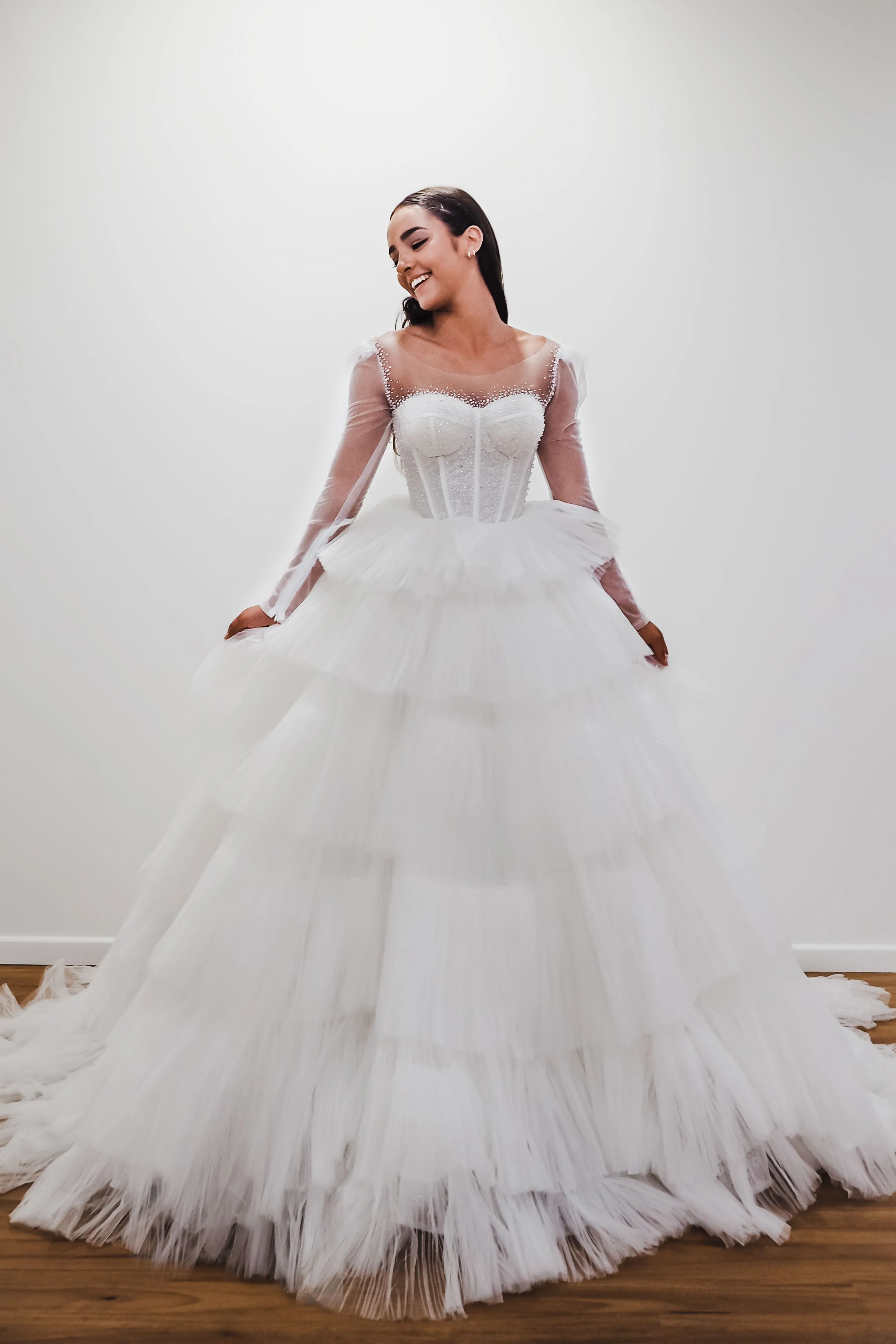 White wedding dress with a bushier top and a bushier puffy layered skirt.